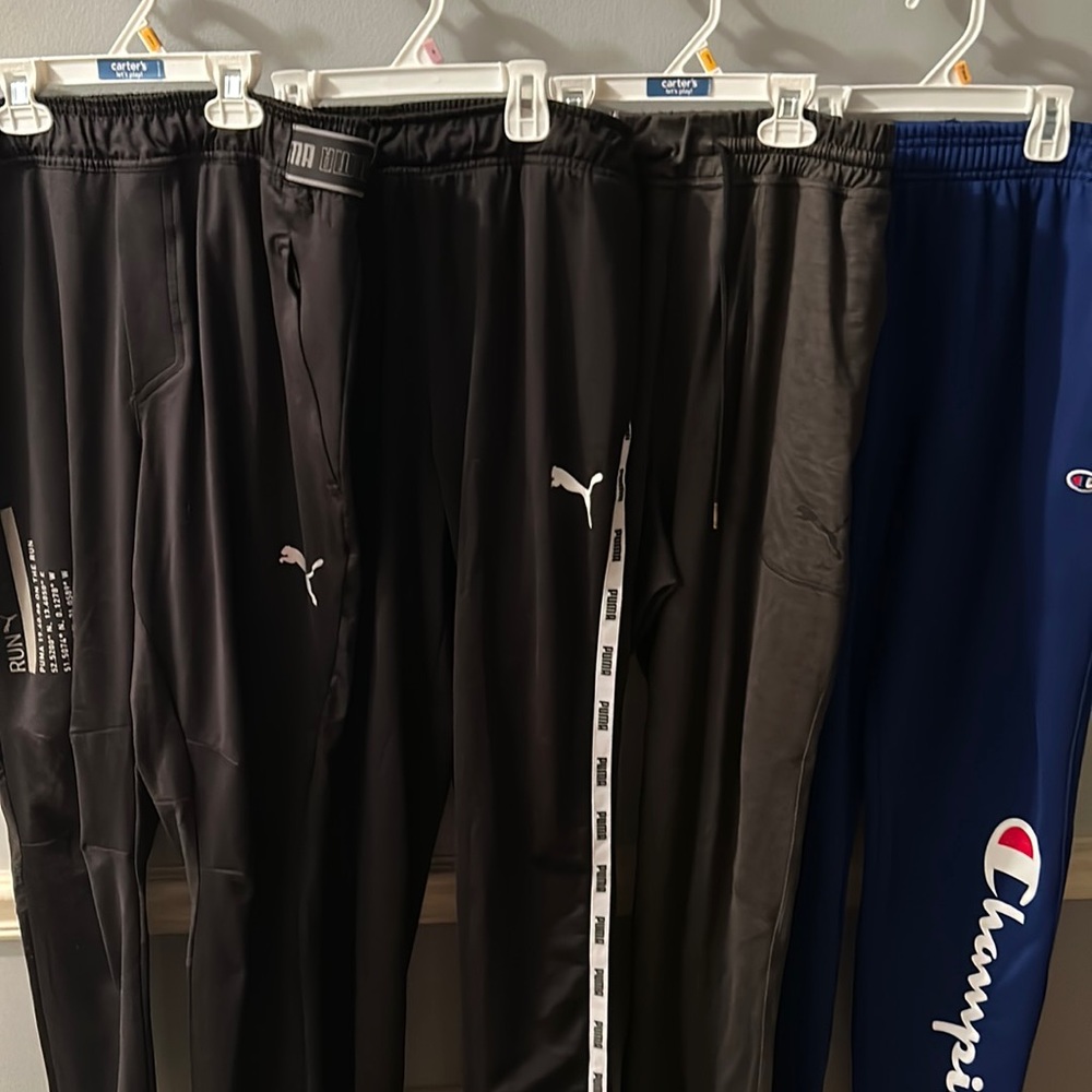 Five pair of men’s athletic pants- four Puma and one Champion. Size Medium